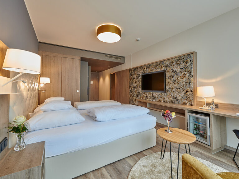 Auf dem Bild ist das Premium Doppelzimmer mit dem großen Bett an der einen und dem Fernseher an der anderen Wand zu sehen