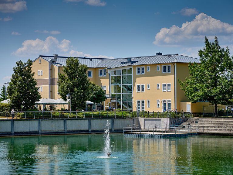 Das Bild zeigt die gelbe Fassade des Hotels am See