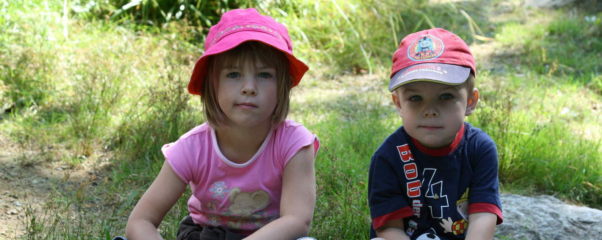 Zwei Kinder sitzen auf einem Stein