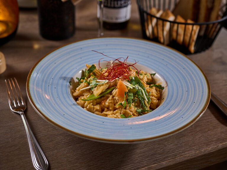 Ein Teller mit Thailändischem rotem Reiscurry, welches auch für Veganer geeignet ist, steht auf einem Tisch